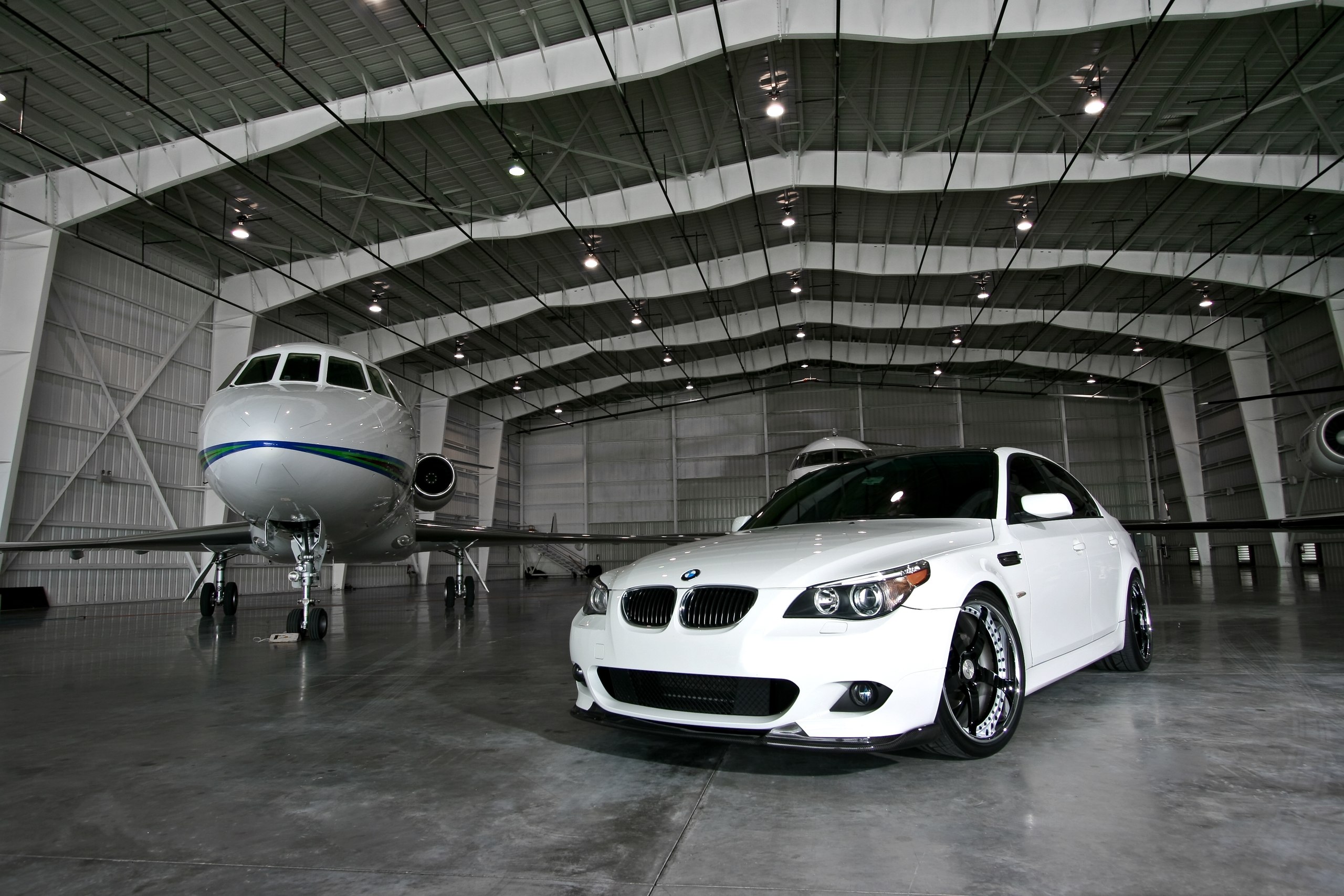Белый BMW 5 series в ангаре для личных самолетов